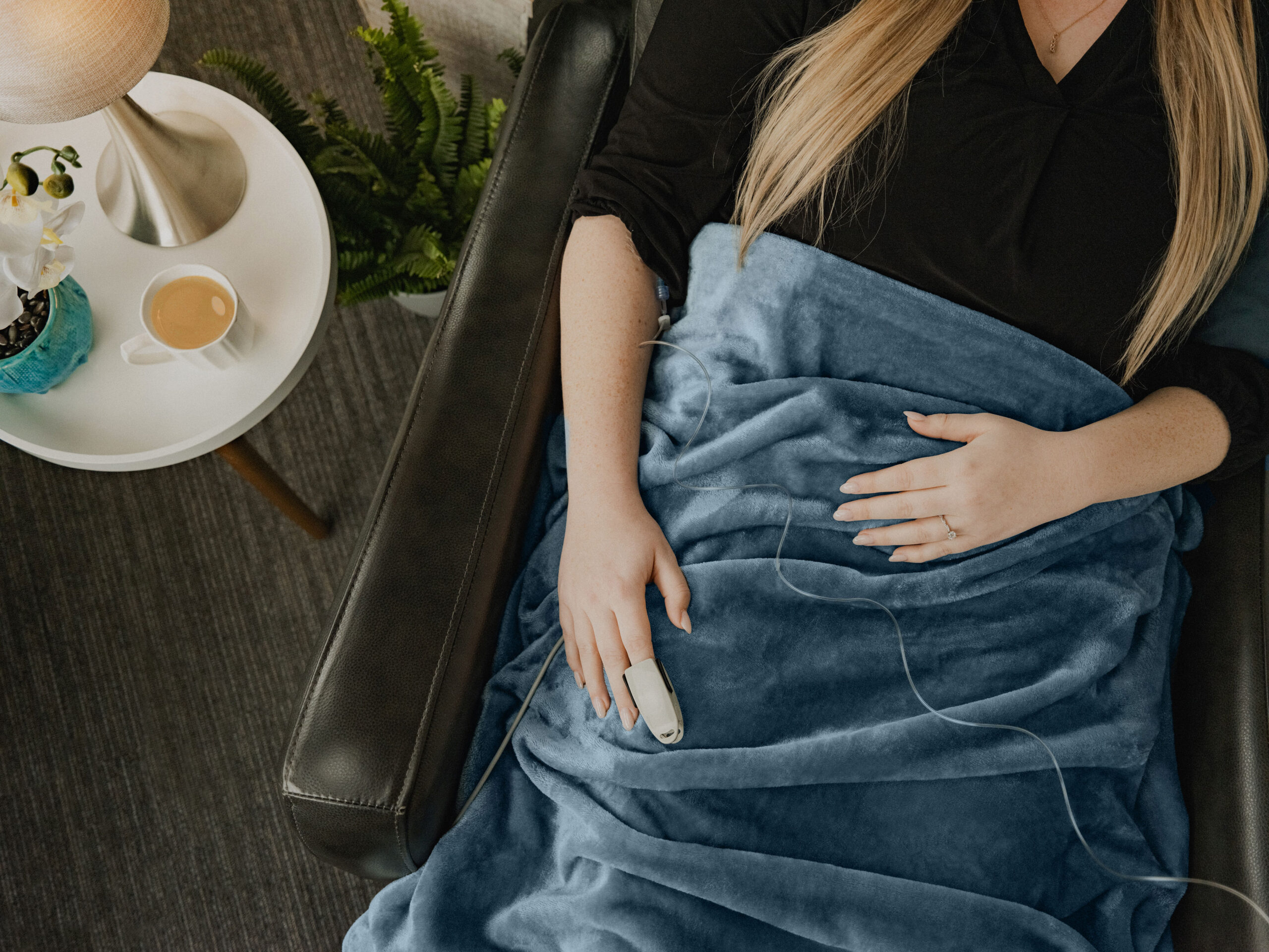 A patient relaxing under a soft blanket with a warm drink during a comfortable infusion