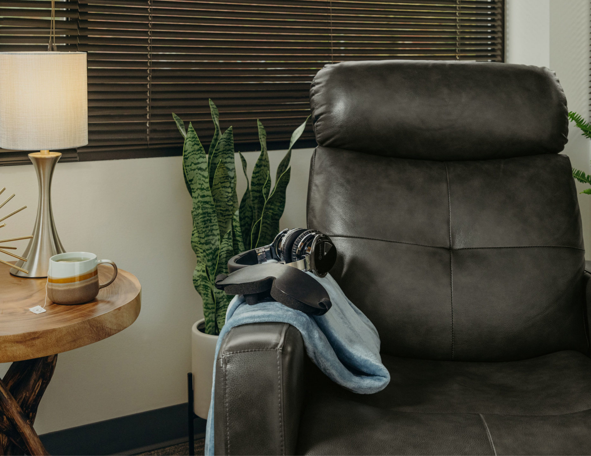 A calm private Spravato treatment room with a recliner, noise-cancelling headphones, eye mask, and soft blanket