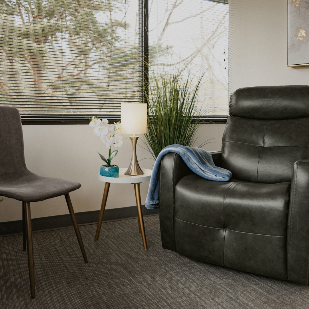 A private treatment room with a comfortable recliner and a window overlooking trees